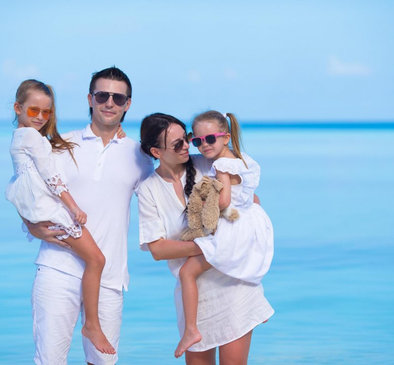 famiglia vestita di bianco con occhiali sole al mare